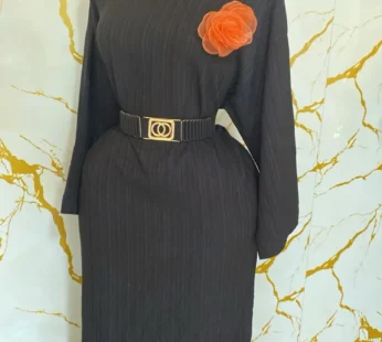 Robe noire élégante avec ceinture noire et broche rouge